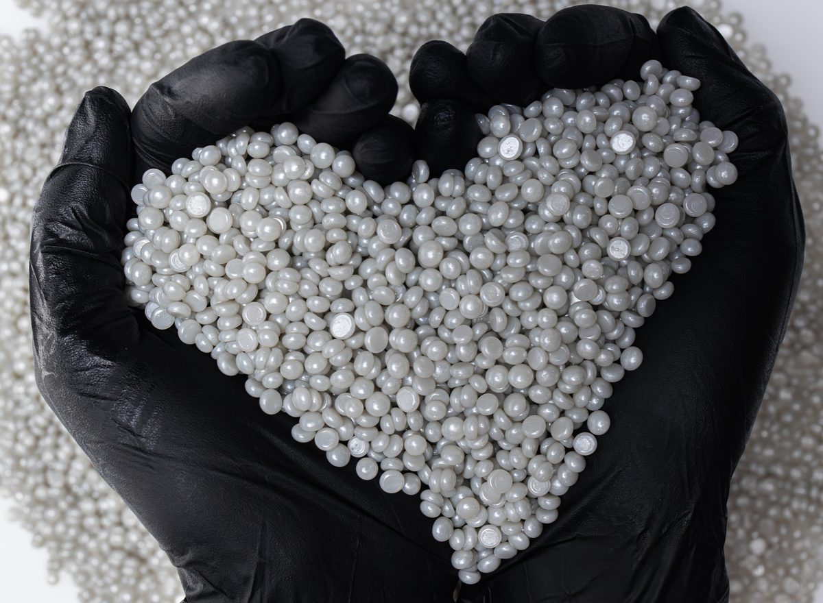 Gloved hands holding a heart of Nova hard wax microbeads