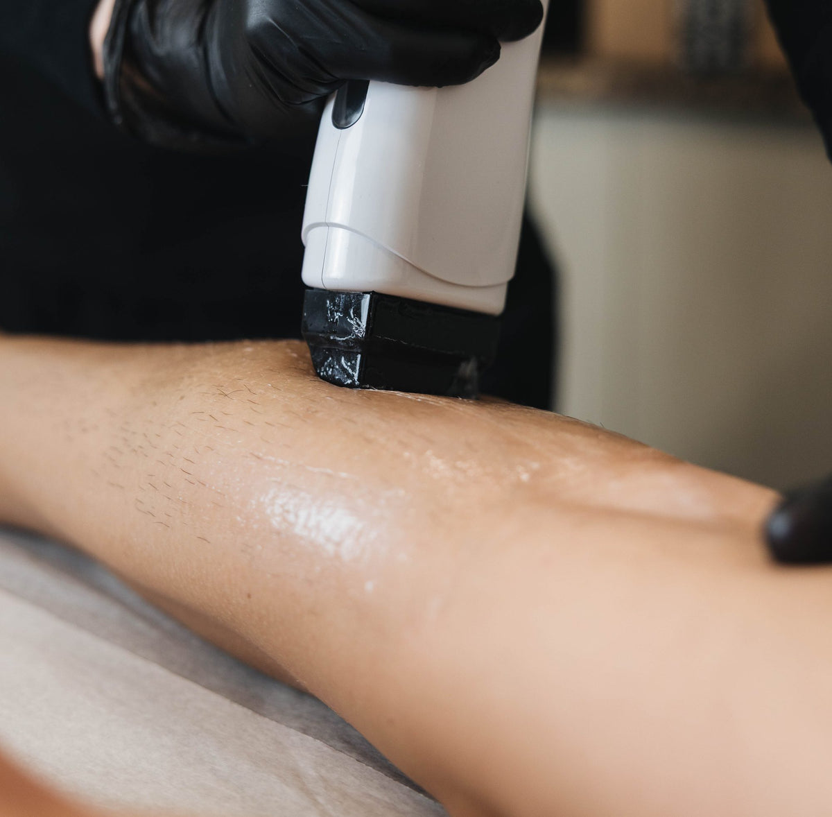 Esthetician applying Nova Wax roll-on wax to a client's leg with the roll-on warmer